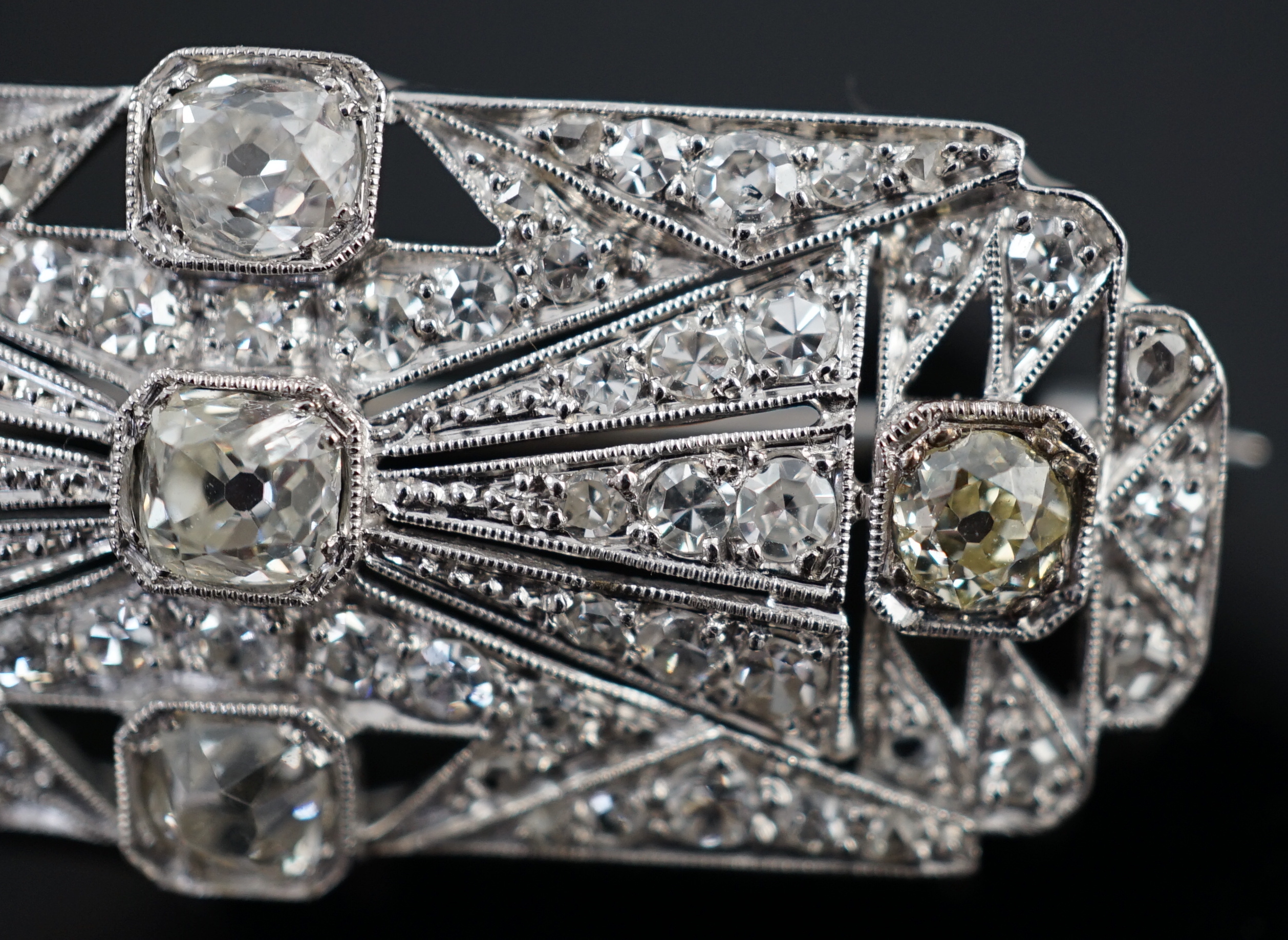 An Art Deco pierced platinum and millegrain set diamond cluster shaped rectangular brooch